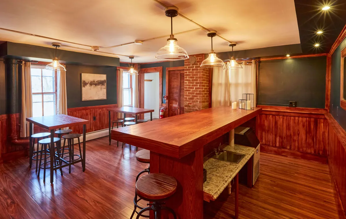 The image features a cozy bar counter with stools, set against a backdrop of brick walls and large windows. The scene is set for casual dining, social gatherings, and entertaining guests. The warm, welcoming atmosphere speaks to memorable shared moments around food and drink.