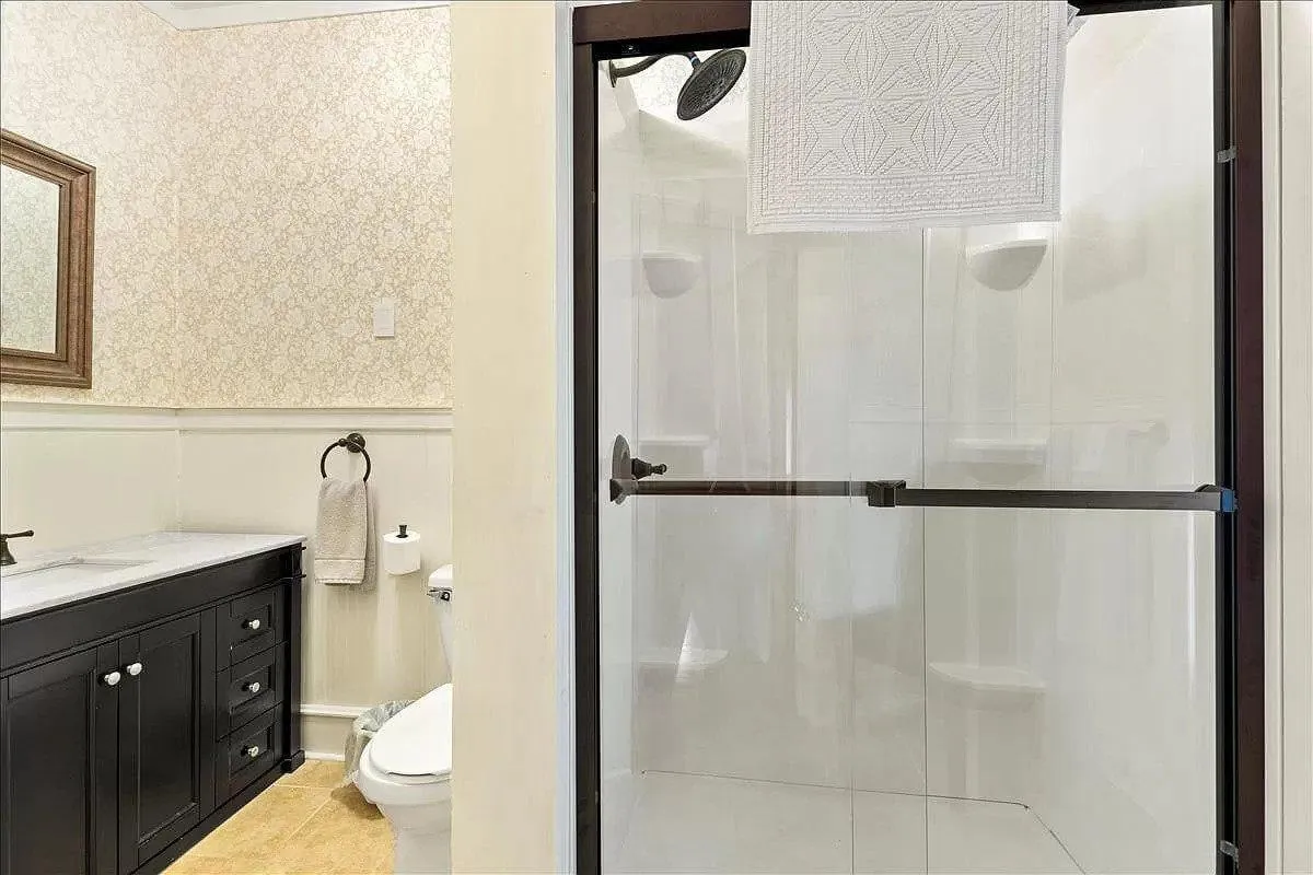 This bathroom image showcases a stylish vanity with drawers, a glass shower enclosure, and a decorative mirror. The clean lines and contemporary fixtures evoke a spa-like, calming atmosphere perfect for rejuvenation.